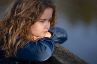 Hayalperest çocuk temiz havanın tadını çıkarıyor. Tasasız bir çocuğun portresi. Hayal gücünde sarışın bir çocuk. Huzurlu çocuk doğada dinleniyor. Geleceği düşünen bir çocuk. Küçük şirin hayalperest portresi. Çocuk yüzü