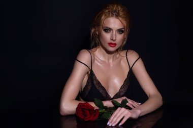 Kırmızı gül tutan baştan çıkarıcı kadın. Çekici, sevimli, rüya gibi bir kızın portresi. Elinde kırmızı güller, siyah stüdyo arka planında izole edilmiş.