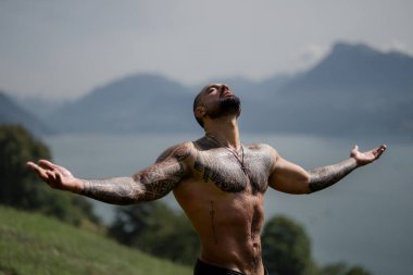 Kaslı adam temiz hava soluyor. Seksi erkek doğada dinleniyor. Sağlıklı gövde güçlü beden güçlü akıl. Doğa üzerine kaslı fitness modeli. Doğada spor. Fiziksel ve zihinsel bakım. Ahenkli spor modeli