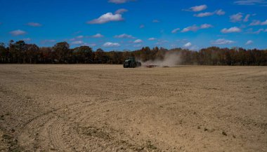 Traktör tarlayı sürüyor. Kırsalda sonbahar çiftçiliği. Kırsal tarım arazilerinde traktör. Toprakta çalışan tarım makinesi ya da traktör. Çekici tarla sürme çiftliği. Çiftlik arazisi