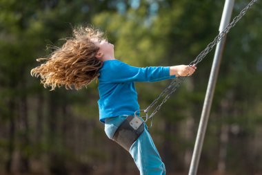 Bahar parkında sallanan neşeli çocuk. Sarı saçlı küçük bir çocuk salıncakta sallanıyor. Parkta gülümseyen mutlu çocuk. Mutlu çocukluk anları. Çocuk dışarıda oynuyor. Çocuk salıncakta eğleniyor. Çocuklar için açık hava oyunu