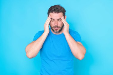Baş ağrısı migreni konsepti. Yorgun adam baş ağrısından muzdarip, gözleri kapalı, kafaya dokunmaktan bitap düşmüş. Adam baş ağrısından parmaklarıyla şakaklara dokunuyor. Şiddetli baş ağrısı