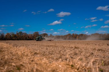 Traktör tarlayı sürüyor. Kırsalda sonbahar çiftçiliği. Kırsal tarım arazilerinde traktör. Toprakta çalışan tarım makinesi ya da traktör. Çekici tarla sürme çiftliği. Çiftlik arazisi