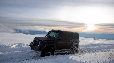 01.02.2021, Karpatlar. Gün batımında kar içinde off-road SUV. 4x4 jipli bir kış seferi. Kış doğasında zorlu bir off-road gezisi. Kış off-road. Kar yolunda macera gezisi. Kış yolları