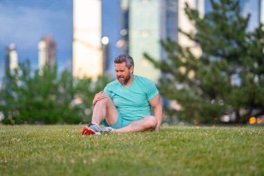 Koştuktan sonra diz ağrısı. Dizinden yaralanan bir adam. Egzersiz bacak ağrısına neden oluyor. Koşu diz travmasına yol açıyor. Açık hava egzersizi ve diz incinmesi. Şehir parkında koşudan kaynaklanan sağlık sorunları. Bacağım acıyor.