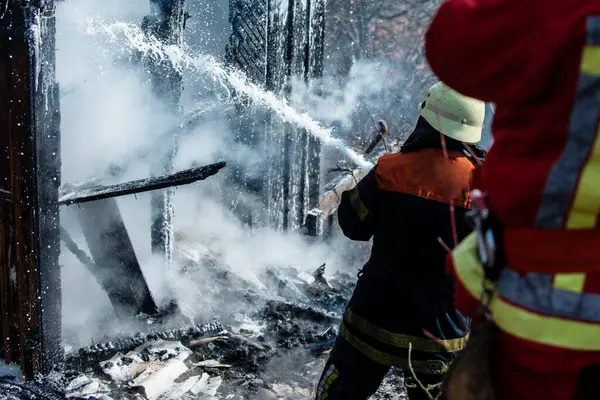 İtfaiyeci yangını söndürdü. Cesur itfaiyeci evdeki alevlerle savaşıyor. Üniformalı itfaiyeciler yanan evde. İtfaiyeci yangını kontrol etmek için hortum kullanır. İtfaiyecilik konsepti. Kasklı itfaiyeci yanıyor.