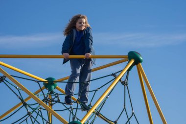 Çocuk dışarı tırmanıyor. Oyun parkına tırmanan aktif bir çocuk. Çocuk parka tırmanıyor. Mutlu çocuk dışarıda oynamaktan hoşlanıyor. Sevimli çocuk oyun alanında eğleniyor. Çocuk parka tırmanıyor