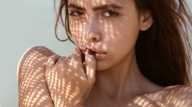 Genç ve seksi bir kadının şehvetli portresi parmağını yalıyor. Stüdyo gölgesinde poz veren şehvetli bir kadın. Güzellik kraliçesinin moda çekimi. Moda makyajlı şehvetli bir manken. Şehvetli kız modası.