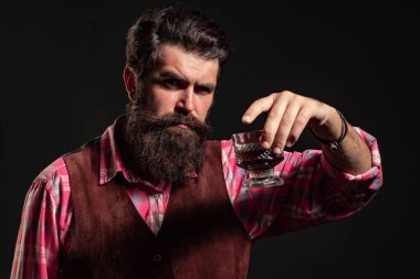 Sakallı adamın tuttuğu viski bardağı. Barda yalnız başına viski içen adam. Klasik bardakta viski. Viski tadı retro tarzında. Pahalı viski. Konyak ya da viski. Alkolik içecek.