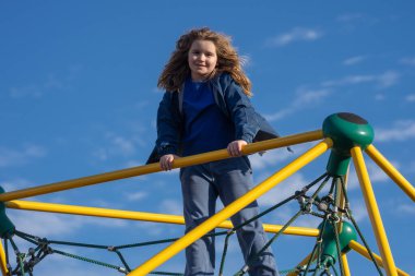 Çocuk dışarı tırmanıyor. Oyun parkına tırmanan aktif bir çocuk. Çocuk parka tırmanıyor. Mutlu çocuk dışarıda oynamaktan hoşlanıyor. Sevimli çocuk oyun alanında eğleniyor. Çocuk parka tırmanıyor