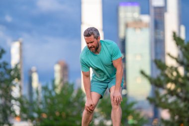 Diz üstüne bacak ağrısı. Koşu sırasında bacağım ağrıyor. Dizini tutan yaralı bir adam. Koştuktan sonra bacakları ağrıyor. Dizinden yaralanan bir adam. Antrenman bacak ağrısı. Koşu diz travmasına yol açıyor. Bacak ağrısı.