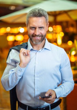 İş adamı gece lambasında telefonda konuşuyor. İş adamı cep telefonu kullanıyor. Olgun iş adamı internette sohbet ediyor. İş adamı bir arama yapıyor. İş konuşmaları. İş adamı dışarıda telefonla konuşuyor.