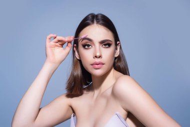 Eyebrow shaping, woman combs eyebrows with a brus. Eyebrow line. Makeup and cosmetology concept. Female model with long eyelashes and thick eyebrows. Perfect shaped brow