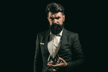 Sakallı adamın tuttuğu viski bardağı. Barda yalnız başına viski içen adam. Klasik bardakta viski. Viski tadı retro tarzında. Pahalı viski. Konyak ya da viski. Alkolik içecek.