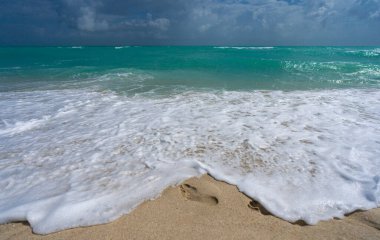Kuma ayak basar. Deniz dalgaları. Yaz dönemi. Okyanus suyu hareketi. Okyanus sıçrama dalgası arka planı. Derin mavi deniz plajı. Turkuaz dalga arka planı. Rüya gibi egzotik deniz sahili arka planı