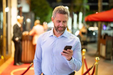 Gece yarısı iş adamı telefonda konuşuyor. İş adamı cep telefonu kullanıyor. Olgun iş adamı internette sohbet ediyor. İş adamı bir arama yapıyor. İş konuşmaları. İş adamı dışarıda telefonla konuşuyor.