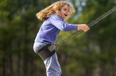 Çocuk salıncakta eğleniyor. Çocuk bahçesinde mutlu bir çocuk. Havada sallanan kaygısız çocuk. Mutlu çocuklar dışarıda oynuyor. Sarışın çocuk heyecandan titriyor. Dışarıdaki oyuncu çocuk. Komik çocuk suratı