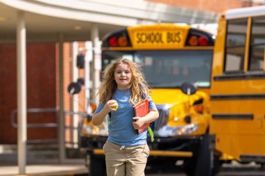 Okul otobüsü dışarıda çocuk öğrenciyi bekliyor. Sırt çantalı sarışın çocuk ve okula gitmek için not defterleri. Devlet okuluna kadar yürüdüm. Amerikan okulunda eğitim, öğrenim ve bilgi kavramı