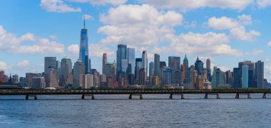 New York şehri. New York şehir manzarası. New York 'taki Lower Manhattan ve One World Trade Center. Manhattan 'ın gökdelenleri New York körfezinin dalgalanan sularının yanında mavi gökyüzüne karşı. New York gökdelenleri