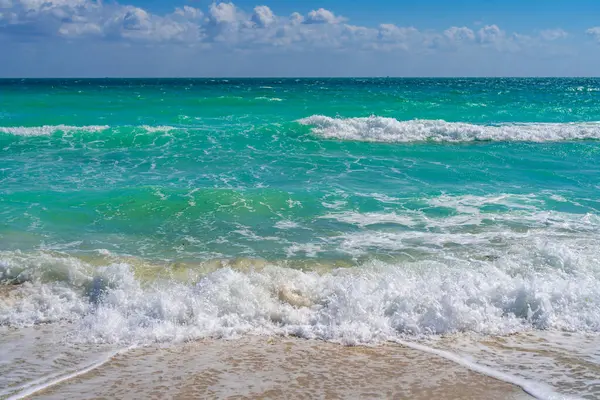 Turkuaz deniz dalgası hareketi. Yaz plajı. Sakin deniz. Lüks sahil beldesi. Parlak gökyüzü ve sahilde dalgalar. Güzel köpüklü kıyı şeridi. Deniz arka planı. Mavi okyanus. Kumlu okyanus plajı. Deniz dalgaları