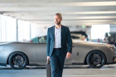 Lüks arabanın yanında zengin bir işadamı. Başarılı iş adamı. Şık ceketli, olgun, zengin bir iş adamı. Takım elbiseli zengin bir iş adamı dışarıda yürüyor. Lüks başarılı iş adamı