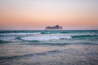 Okyanusta bir gemi turu. Okyanusta lüks bir yolcu gemisi. Yolcu gemisi olan Miami Plajı. Turkuaz su ve yolcu gemisi. Kıyıya yakın bir turist gemisi. Okyanus dalgaları ve gemi teknesi