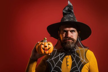 Cadılar Bayramı balkabaklı komik bir model. Cadılar Bayramı şapkalı balkabaklı insan portresi. Şeker mi şaka mı? Cadılar Bayramı şapkalı korkunç hippi. Cadı şapkalı adam balkabağını tutuyor. Mutlu Cadılar Bayramı