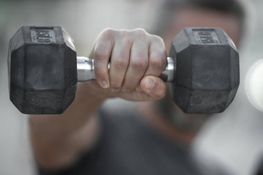 Dambıllar kol kola. Yetişkin bir adamın dambılları dışarı kaldırması. Kol kasları dambıl egzersizi yapıyor. Kol halteri tutun. Dambılı bir erkek kolunun yakın çekimi.