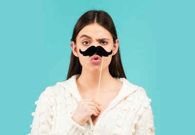 Kız, bıyıklı ve aksesuarla mutlu. Çizgi roman kadın portresi. Bıyıklı komik surat. Elinde kağıt bıyıklı parti çubuğu tutan komik kadın. Komik bıyıklı kız