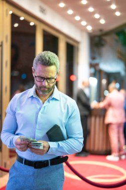 Gece kulübünün yakınında cüzdanı ve parası olan zengin bir iş adamı. Gece kulübü partisindeki zengin iş adamı. Gece lambalarında kendinden emin zengin bir adam. İş adamları için zengin bir gece hayatı. Zenginlik kavramı