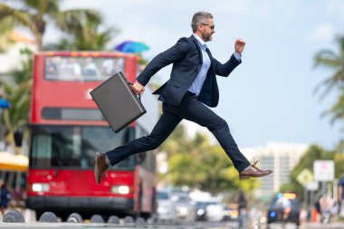 İş atlayışı. Caddeye atlayan çılgın bir iş adamı. Takım elbiseli bir işadamı geç kaldı ve atladı. Sıçrama hareketiyle meşgul bir iş adamı. Kendine güvenen işadamı heyecanla zıplıyor.