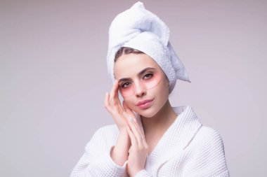 Göz bandı. Göz altlarında kolajen pedleri olan güzel kadın yüzü. Stüdyo çekimlerinde genç bir kadının gözlerinin altına kolajen bantları yapıştırılmış taze ve sağlıklı bir derisi var. Kafasına havlu takıyor ve yüz bakımı yaptırıyor.