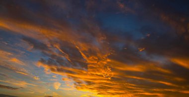 Gün doğumunda gökyüzü. Günbatımı arka planı. Gökyüzündeki bulutların arasından gün doğumu. Gündoğumu renkleriyle alacakaranlık gökyüzü. Yumuşak ışıkla huzurlu bir şafak. Bulutlu dramatik günbatımı. Açık gökyüzünde gün ışığı