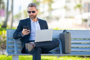 Kendine güveni tam bir iş adamı. Yaz parkında dizüstü bilgisayar ve telefonla bankta oturuyor. Başarı uzaktan yapılan bir iş. Orta yaşlı iş adamı tatilin tadını çıkarıyor. İş adamı bir bankta mola veriyor.