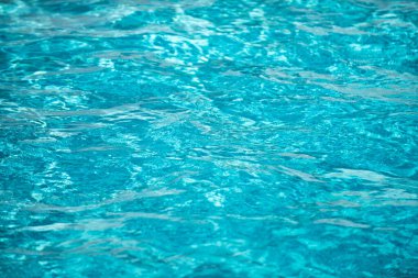 Yüzme havuzundaki mavi suyun arka planında güneş yansıması, havuzda dalgalı su dalgaları. Temiz su arkaplanı