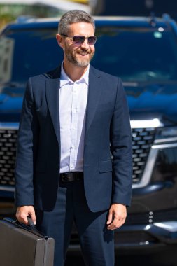 Olgun bir iş adamı. Lüks bir arabanın yanında duran zengin bir işadamı. Küresel. Endüstri lideri. Başarılı bir iş. Pahalı bir arabanın önünde duran şık, lüks bir iş adamı.