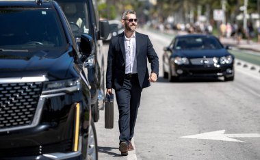 Dışarıdaki yakışıklı iş adamı. Lüks bir arabanın yanında duran zengin bir işadamı. Küresel. Başarılı bir iş. Zarif bir iş adamı pahalı bir arabanın önünde duruyor. Başarılı iş adamı