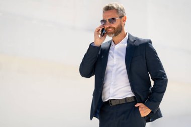 Ofis çalışanı dışarıda cep telefonuyla konuşuyor. Cep telefonunda iş adamı konuşması. İş adamı telefon görüşmesi yapıyor. Şık bir iş adamı telefon kullanıyor. İş görüşmesi. Meşgul işadamı telefonda konuşuyor.