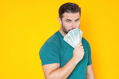 Sarı stüdyoda nakit para tutan zengin bir adam. Büyük şans, afiş. Dolar nakit para konsepti. Nakit para kazanmak için sevinir, şanslı para. Nakit parası olan bir adam. Finansal şans ve başarı