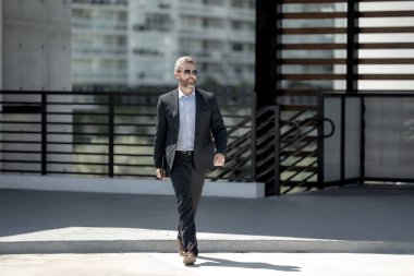 Başarılı bir iş adamı dışarıda dizüstü bilgisayarla dolaşır. Kendine güvenen iş adamı dizüstü bilgisayarı dışarıda tutuyor. Takım elbiseli, olgun, serbest çalışan bir iş adamı. Finans işi. Takım elbiseli zengin iş adamı