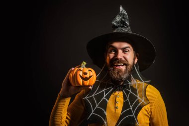 Cadılar Bayramı balkabaklı komik bir model. Cadılar Bayramı şapkalı balkabaklı insan portresi. Şeker mi şaka mı? Cadılar Bayramı şapkalı korkunç hippi. Cadı şapkalı adam balkabağını tutuyor. Komik Cadılar Bayramı