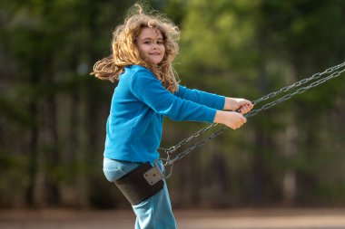 Heyecanlı çocuk eğleniyor. Çocuk bahçesinde mutlu bir çocuk. Havada sallanan kaygısız çocuk. Mutlu çocuklar dışarıda oynuyor. Sarışın çocuk heyecandan titriyor. Dışarıdaki oyuncu çocuk. Komik çocuk suratı