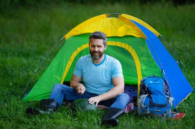 Adam ağaçların altında dinleniyor. Açık hava seyahati. Doğada kamp yapmak. Doğadaki özgürlük. Yaz kampı. Yürüyüş ve kamp macerası. Açık hava yaşam tarzı ve rahatlama. Ormanda bir tatil. Seyahatte dinleniyorum.