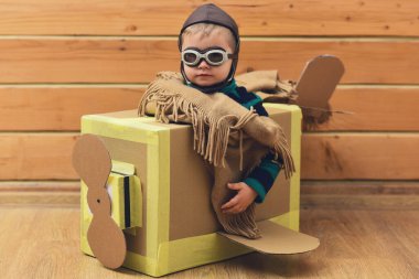 Çocuk hayali kanatlarla oynuyor. Hayalperest çocuk uçmayı hayal eder. Karton kanatlar hayal gücünü harekete geçirir. Yaratıcı çocuk pilotluk oynuyor. Çocuklar hayal gücüyle oynarlar. Çocuklar evde oyuncak uçakla oynuyorlar.