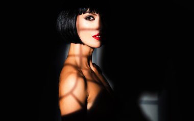 Genç, çıplak, seksi bir kadının şehvetli portresi. Stüdyo gölgesinde poz veren seksi manken. Güzellik kraliçesinin moda çekimi. Moda makyajlı seksi manken. Seksi esmer kadın.
