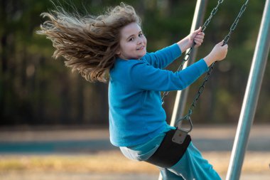 Dışarıda sallanan mutlu çocuk. Salıncakta gülen çocuk. Oyun bahçesinde oynayan neşeli çocuk. Heyecanlı çocuk salıncakta sallanıyor. Yaz parkındaki sevimli çocuk. Parkta sallanan oyuncu çocuk. Mutlu çocukluk