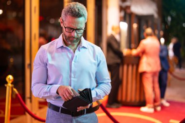 Zengin bir iş adamı cüzdanını elinde tutuyor. Zengin bir işadamı para sayıyor. Cüzdanı ve parası olan zengin bir adam. Şehir gece hayatı işadamı cüzdanı tutuyor. Zengin yaşam tarzı