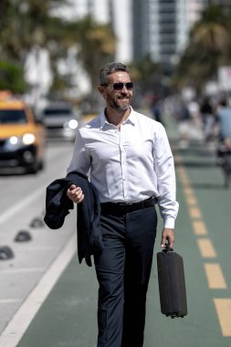 İş adamı işe yürüyerek gider. İspanyol işadamı sokakta güvenle yürüyor. Ofis çalışanı ofise gidiyor. Orta yaşlı iş adamı şehirde yürüyor. Yazlık kıyafetli bir iş adamı.