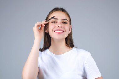 Eyebrow shaping, woman combs eyebrows with a brus. Eyebrow line. Makeup and cosmetology concept. Female model with long eyelashes and thick eyebrows. Perfect shaped brow