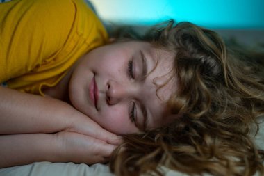 Çocuk yatakta uyuyor. Tatlı çocuk uyuyor. Çocuklar için yastık ve battaniye. Çocuk karanlık odada uyuyor. Evdeki bir yatakta uyuyan çocuk